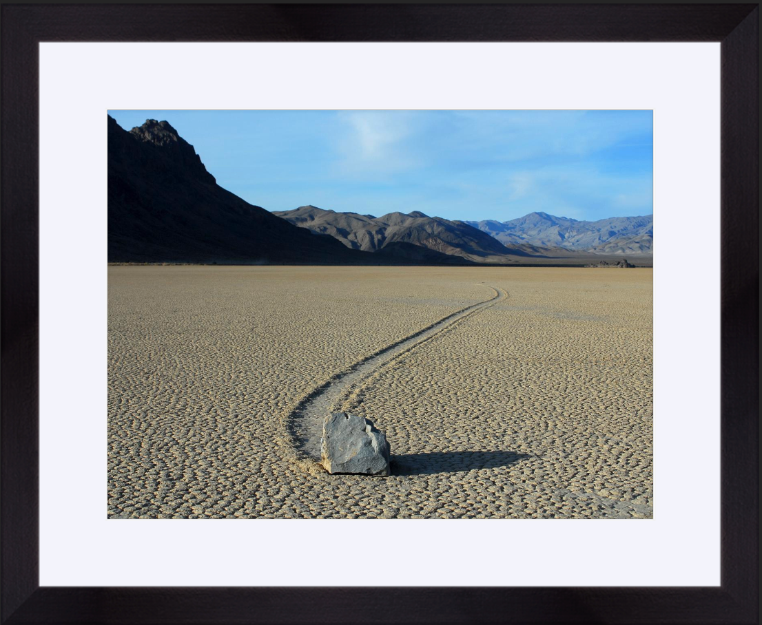 Desert landscape with a sliding rock and mountains in the background; framed photograph