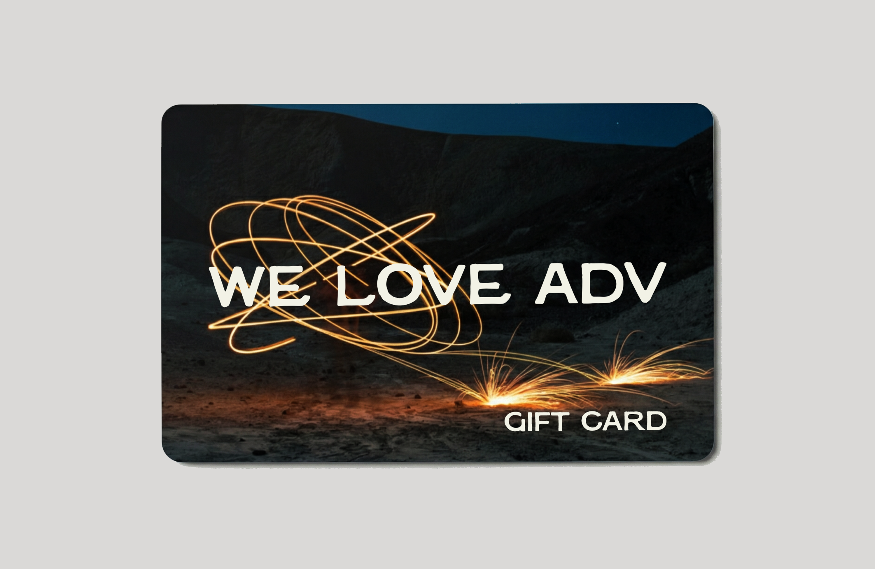 Gift card with 'WE LOVE ADV' text and sparks of light on a desert night background.